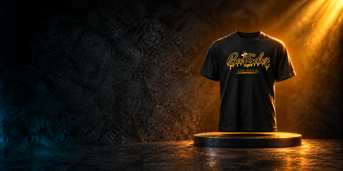 Black Bee Sober Live Better signature T-shirt above a thin round platform under a warm gold spotlight.